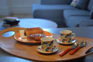 - une table en bois avec deux tasses et une assiette de gâteau dans l'établissement Burdigala Homes - Appart rue Ausone, à Bordeaux