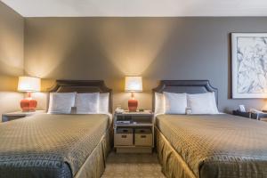 two beds in a hotel room with two lamps at Proximity Hotel in Greensboro