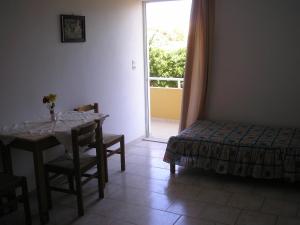 1 dormitorio con mesa, cama y ventana en Dimitra Apartments, en Gouves