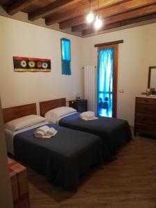 a bedroom with two beds and a window with blue curtains at Il Podere della piazza in Scarperia