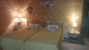 two beds in a room with wooden walls at La Bonardière in Gevry