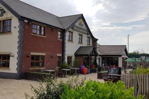 a brick building with tables and chairs in a courtyard at Meadow House- Driveway Parking and Fireplace in East Kilbride