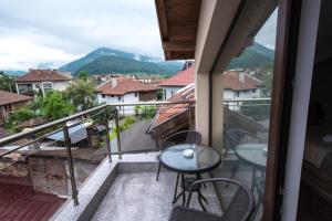 a balcony with a table and chairs and mountains at Etobicoke -Стаи за гости in Etropole