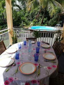 a table with plates and glasses on a deck with a pool at residence cattanies in Sainte-Anne