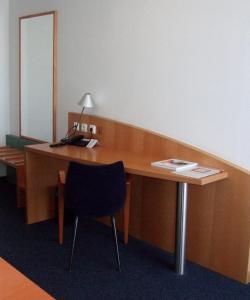 escritorio de madera con silla y teléfono en Sporthotel Wiedenbrueck, en Rheda-Wiedenbrück