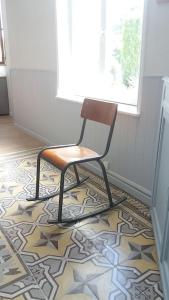krzesło siedzące na podłodze wyłożonej kafelkami w obiekcie La buissonnière w mieście Leuilly-sous-Coucy