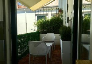 a patio with white chairs and plants in a building at Le Suite del Duomo in Cava deʼ Tirreni