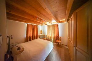 a bedroom with a white bed and wooden ceilings at Casa Ross da Fabio in Livigno