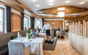 a man standing in a restaurant with two tables at Natur & Aktiv Hotel Rogen in Mühlbach