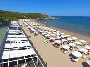 Ein Strand mit einem Haufen Regenschirme und Menschen darauf. in der Unterkunft Valtur Baia del Gusmay Beach Resort in Peschici