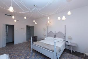 Dormitorio blanco con cama y techo en Palazzo Conti Camere & Suites, en Scicli