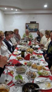 un grupo de personas sentadas alrededor de una larga mesa llena de comida en Guest House Nona en Kutaisi