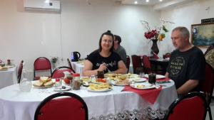 Ein Mann und eine Frau sitzen an einem Tisch mit Essen in der Unterkunft Guest House Nona in Kutaissi