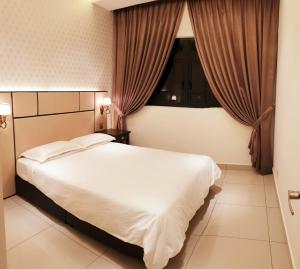 a bedroom with a large white bed and a window at Meridin in Nusajaya