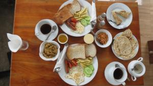 a wooden table topped with plates of breakfast foods at Green Ocean Bay in Arugam Bay