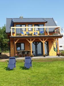 ein Haus mit zwei Stühlen auf dem Rasen in der Unterkunft Domek z widokiem na jezioro - Domek Jerzy in Kruklanki