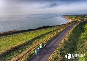 a group of people walking down a road next to the ocean at No 12 B&B in Dungarvan