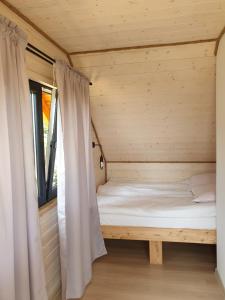 Bett in einem Holzzimmer mit Fenster in der Unterkunft Domek z widokiem na jezioro - Domek Jerzy in Kruklanki