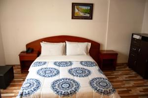 ein Schlafzimmer mit einem Bett mit einer blau-weißen Decke in der Unterkunft La Gran Fortaleza B&B in Bogotá