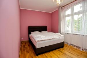 Apartament Diana في كارباش: غرفة نوم بجدران وردية وسرير بملاءات بيضاء