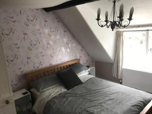 a bedroom with a bed with flowers on the wall at Ham Tree Cottage in Trowbridge