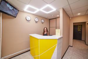 a woman sitting at a yellow counter in a room with clocks at LUNA hotel in Biysk
