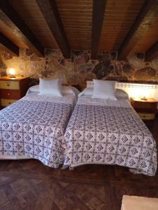 a bedroom with two beds and a stone wall at Casa Valentina in Candeleda