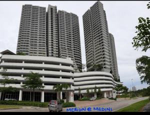 two tall buildings with cars parked in front of them at Meridin in Nusajaya