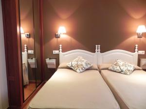 a bedroom with a white bed with two pillows at Hospederia Los Pinos in Llanes