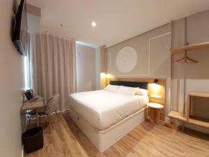1 dormitorio con 1 cama blanca y TV en Habital Suites, en Jaca