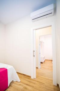 a white bedroom with a red bed and a bathroom at A&S APARTAMENTOS MALAGA I in Málaga