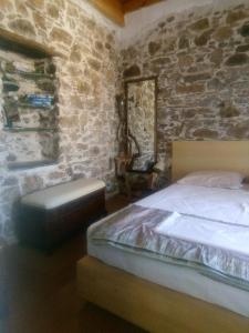 a bedroom with a bed and a stone wall at SAMOS 1880 in Marathokampos