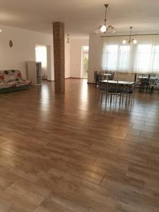 a living room with a wooden floor and a dining room at Pensiunea Alex & Andry in Cordun