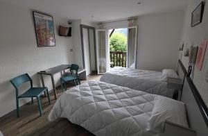 Cette chambre d'hôtel comprend deux lits, une table et des chaises. dans l'établissement Hotel De l'Europe, à Meyrueis