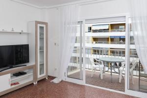 a living room with a tv and a table and chairs at ROS MARY, 7º-14 in Cullera