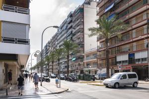a city street with palm trees and a white car at ROS MARY, 7º-14 in Cullera