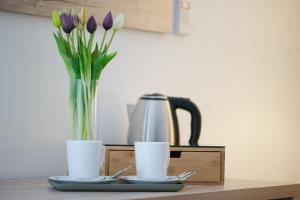 a vase of purple tulips and two cups on a table at Boutique house Oreskovic in Plitvička Jezera
