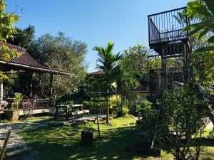 a garden with a wooden bench and a building at Kingfisher House in Sangkhla Buri
