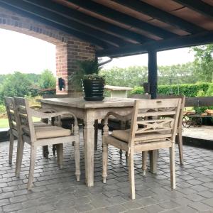 een houten tafel en stoelen op een patio bij Hof Leskensdaele Deluxe in Geraardsbergen