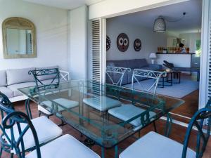 ein Wohnzimmer mit einem Glastisch und Stühlen in der Unterkunft POP'S APPARTEMENTS RESIDENCE MARISOL au bord de la mer in Le Gosier