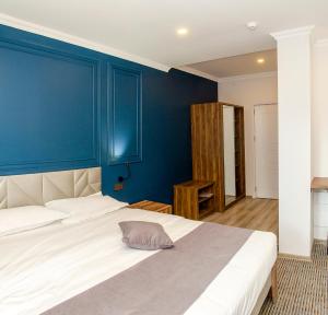 um quarto com paredes azuis e uma cama branca em The Residence Hotel & Cottages em Kojori