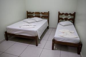 two beds in a room with white sheets and towels at Novo Hotel Paraopeba in Paraopeba