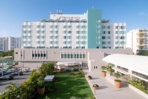 a large white building with a green lawn in front of it at Verdanza Hotel in San Juan