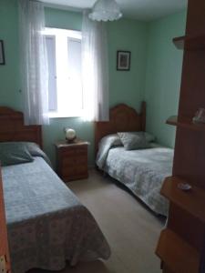 1 dormitorio con 2 camas y ventana en Se alquila piso en Sanxenxo con vistas al mar en Sanxenxo
