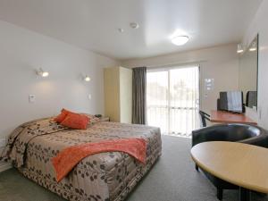 霍奇蒂卡的住宿－Bella Vista Motel Hokitika，一间卧室配有一张床、一张桌子和一个窗户。