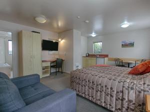 a bedroom with a bed and a couch and a desk at Bella Vista Motel Hokitika in Hokitika