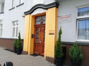 a building with a wooden door and two potted plants at Eldom-NOCLEGI, Kolejowa 15 Wągrowiec in Wągrowiec