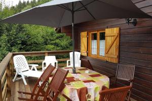 un patio con mesa, sillas y sombrilla en Chalet Kylucru 6 personnes classé 2 étoiles en Xonrupt-Longemer