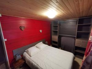 Un dormitorio con una pared roja y una cama. en Chalet Kylucru 6 personnes classé 2 étoiles en Xonrupt-Longemer