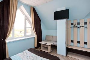 a bedroom with a bed and a tv and a window at Guest House Tri Klena in Velikiy Novgorod